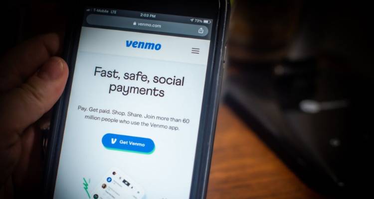 User holding a smartphone displaying the Venmo app homepage, focusing on ‘How Do You Make a Payment to Venmo’.